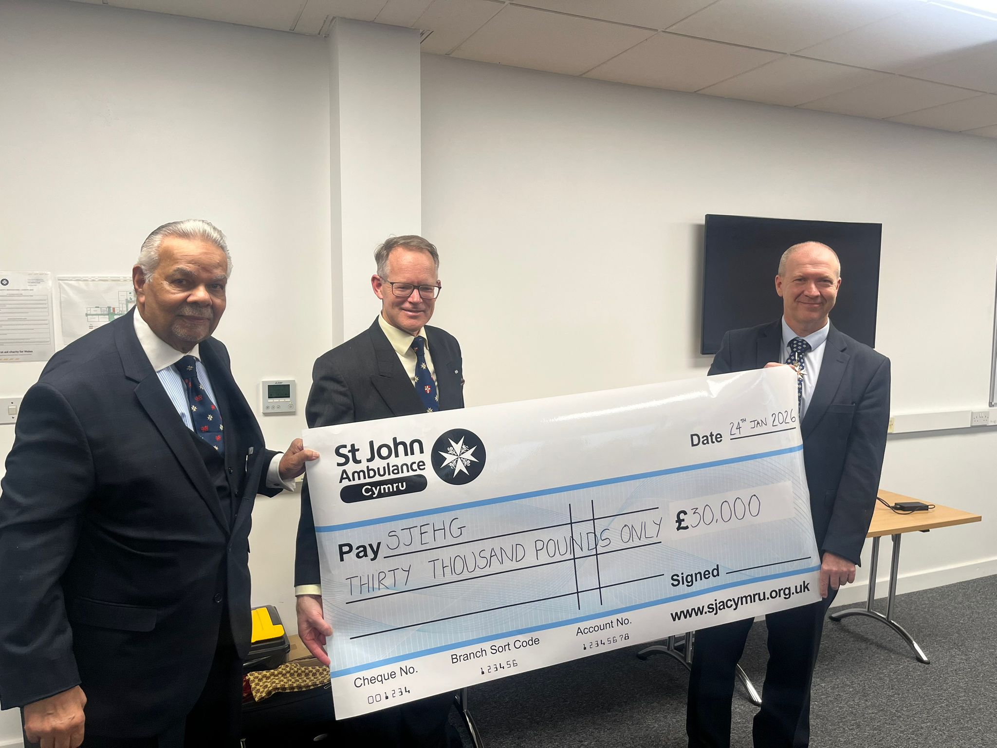 Mr David Verity KStJ MD MA (Oxon) BM BCh FRCOphth, Hospitaller of the Order of St John (centre) receives the cheque on behalf of the St John of Jerusalem Eye Group from Dr Akram Baig CStJ (left), the outgoing Hospitaller of the Priory for Wales and Paul Griffiths OBE KStJ JP DL (right), the Prior for Wales and Chair of the Board of Trustees of St John Ambulance Cymru.